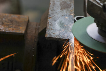 Intense industrial metal grinding work in workshop setting. powerful tool creates shower of hot orange spark and bright light during steel manufacturing process