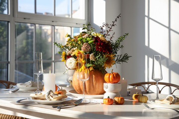 Beautiful bouquet of autumn flowers in pumpkin on served dining table