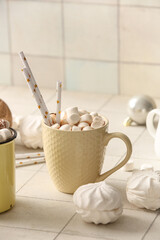 Cup of hot cocoa with marshmallows on white tile background