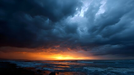 Fototapeta premium Dramatic sunset over a stormy ocean with turbulent clouds and fiery light reflected on the waves