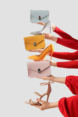 Female hands with stylish women's bags and high heels on grey background