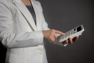 Businesswoman in suit holding calculator on grey background