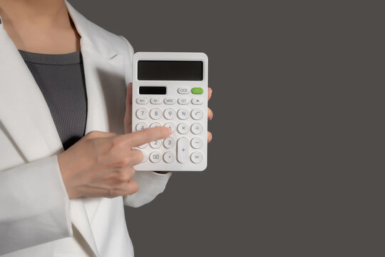 Businesswoman in suit holding calculator on grey background - Powered by Adobe