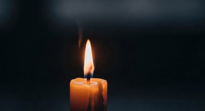 Serene light from a solitary candle flame illuminates the quiet darkness, symbolizing hope, memory, and tranquility