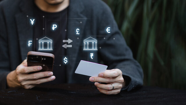 Man using smartphone and credit card for online banking with global currency exchange concept