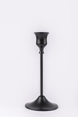 Black metal candle holder in vertical position on white background, modern and minimalist style. Concept of interior design and slow living