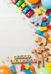 Obraz premium Top-down view of toy cars, blocks, wooden animals, and pastel alphabet cubes forming a soft frame for toddler party theme 
