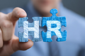 The concept of business, technology, the Internet and the network. A young businessman collects a puzzle with the proper inscription: HR