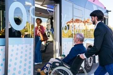 Man in suit pushing disabled senior man in wheelchair onto modern public city bus, promoting accessibility and inclusive transport