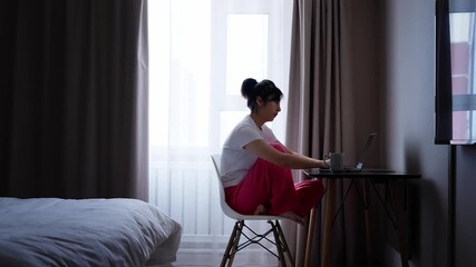Woman using laptop in bedroom - Powered by Adobe