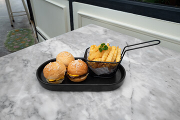 Mini burgers and fries presented on a tray, a delectable fast food combo on a marble table