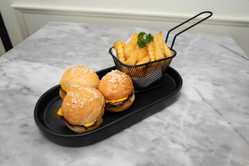 Delicious mini burgers and fries on a stylish tray. A close up shot of mini burger with fries, the fresh food look delicious and appetizing
