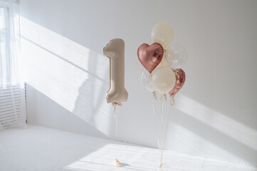 Foil balloons shaped like the number 1 and a heart decorating a wall for a first birthday...