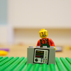 Fototapeta premium Lego minifigure doctor with medical equipment on a green baseplate