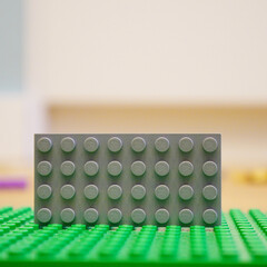 Fototapeta premium A gray Lego brick on a green baseplate, ready for creative building