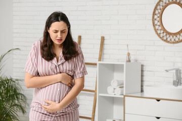 Young pregnant woman suffering from toxicosis in bathroom