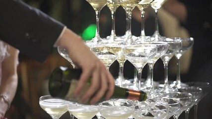 Man pouring sparkling champagne into top glass of pyramid shaped champagne tower at sophisticated wedding celebration, effervescent flow fills each coupe glass below, symbolizing joy and abundance - Powered by Adobe
