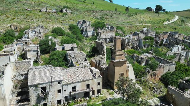 Aerial drone footage of old Poggioreale, Sicily: abandoned ghost town destroyed by the 1968 earthquake, surrounded by hills and silence. Ideal for history, decay, and documentary projects.