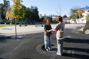 happy mother and teen daughter playing in the playground