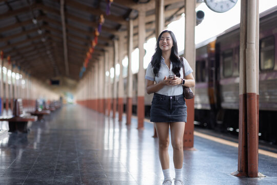 Young woman smiling holding smartphone at train station