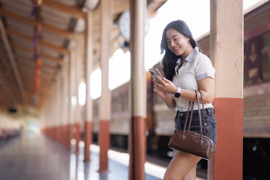 Young woman using smartphone waiting at train station