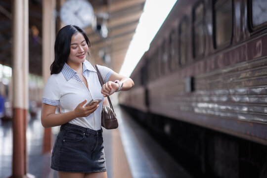 Young woman checking time on smartwatch at train station