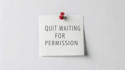 Note with pushpin pinned to white wall displaying a motivational quote
