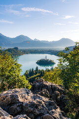 Vertical View of Bled with Castle, Island Church, and Hot Air Balloon over the Lake with Rocks in Foreground