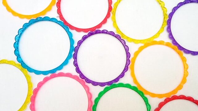 Multicolor plastic bangles rotating on white background, top view, beautiful fashion accessory