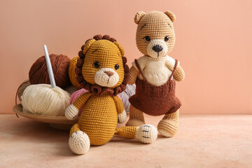 Knitted toys with yarn and crochet hook on grunge table against beige background