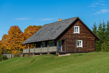 Rustic Wooden Cottage Cabin Surrounded by Autumn Trees and Green Landscape