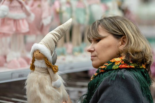 A woman in a Christmas decoration store compares prices on decorations and New Year's toys. New Year's preparations and shopping for the holiday.