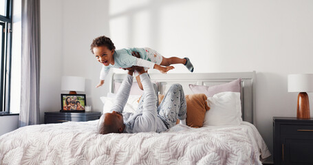 Airplane, dad and playing with child in bedroom, trust or bonding on weekend, happiness and together. Black family, man and flying game with son, father and holding kid in air, love and fun in house © Malik25/peopleimages.com