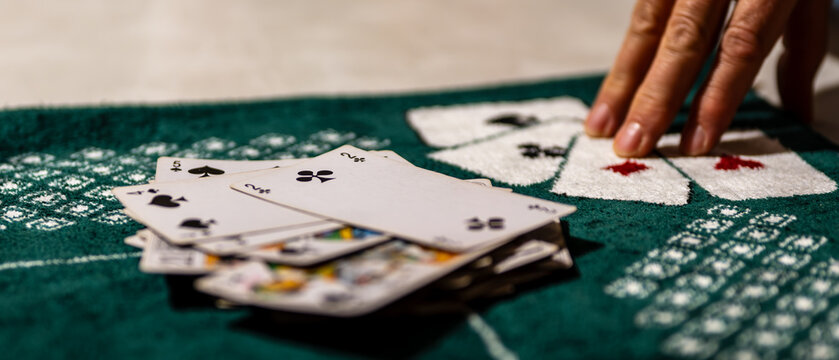 french tarot card game in progress, close-up of playing cards and player’s hand on green felt table. strategic moment captured during a casual evening match symbolizing focus and tension