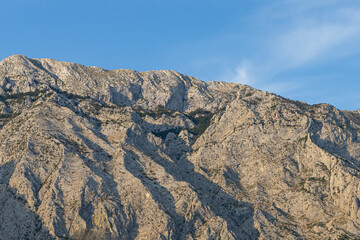 Gray rocks with small vegetation against the sky. Mountain landscape, Croatia. copy space