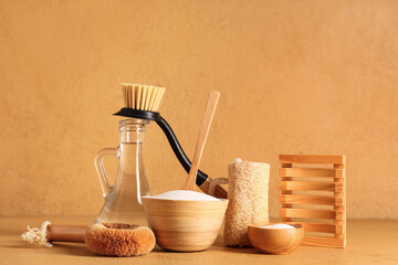 Bowls of baking soda with vinegar and cleaning supplies on orange grunge background