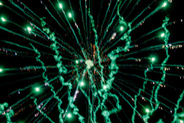 Green fireworks explosion in the night sky above Sainte-Marie-la-Blanche, France. Radiant abstract pattern with smoke trails and bright sparks captured in long exposure