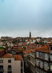 A cityscape of Porto, Portugal, with red-tiled roofs and a prominent tower.