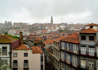 A cityscape of Porto, Portugal, with buildings and a tower under a cloudy sky.