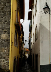 A narrow street between buildings with people walking in the distance.