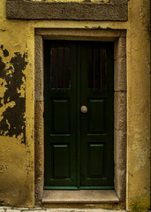 A dark green door with a stone frame and yellow walls.