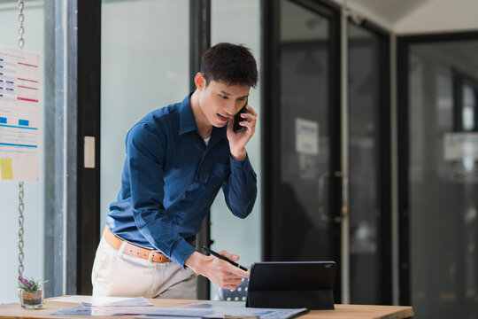 Man multitasking discussing business on phone, pointing tablet