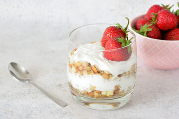 Healthy Yogurt Parfait decorated with Fresh Strawberries with a bowl of strawberries on background