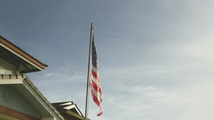 The American flag waves proudly in the wind against the backdrop of Hawaii’s stunning landscape, symbolising
 patriotism and freedom in the tropical paradise. The gentle breeze adds a sense of pride.