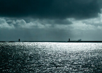 A moody seascape with lighthouses and a stormy sky.