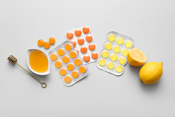 Cough drops in blisters with honey and lemon on white background