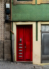 A red door with mailboxes and a window on a building facade.