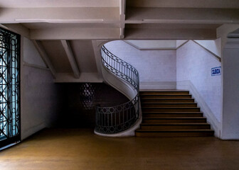 An interior shot of a building's staircase, featuring a spiral staircase and a straight staircase.