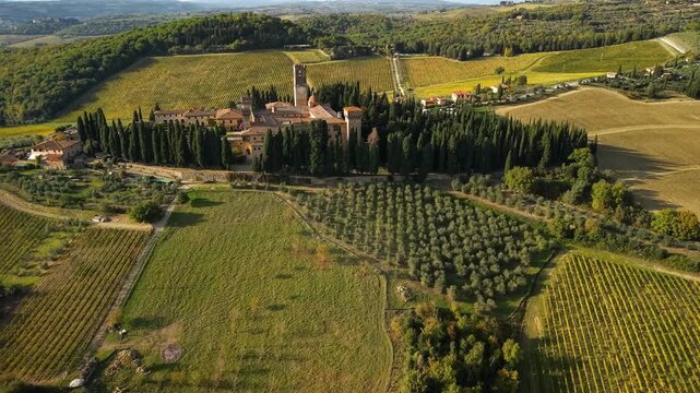 Enotourism in Tuscany aerial 4k view of Chianti Classico vineyards and abbey. Luxury wine travel destination in Italy with medieval architecture and rolling hills. Premium viticulture  