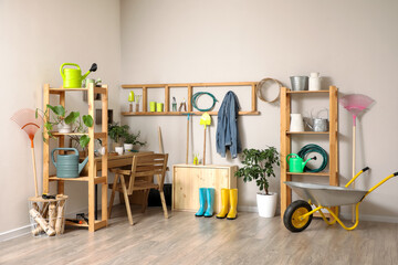 Gardener workspace with table, shelving units and different gardening supplies near light wall